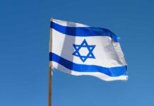 Israeli flag waving against a clear blue sky.