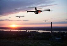 Drones flying over a landscape at sunset.