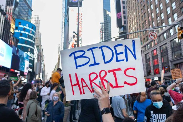 Person holding "Biden Harris" sign in crowded city street.