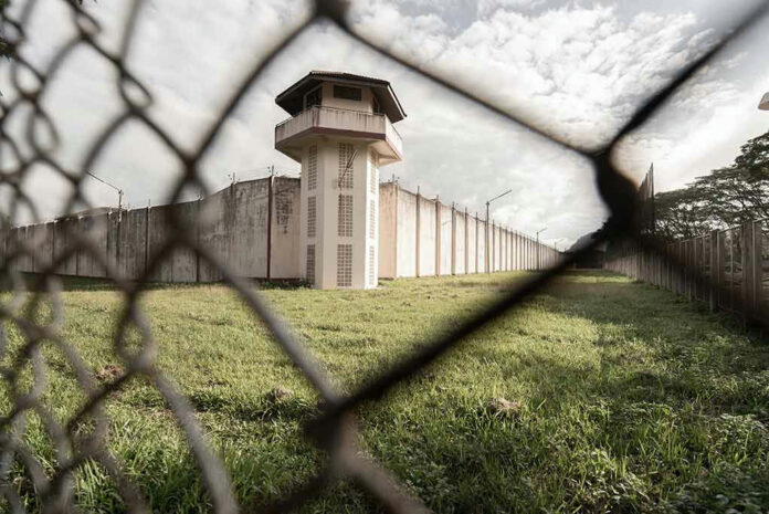 View of prison watchtower through chain-link fence.