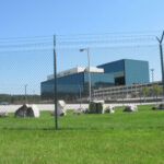 Internment Camp Plan Sparks Bipartisan Fury! Chain-link fence in front of a large modern office complex