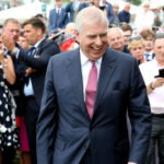 A man in a suit smiling crowd in background.