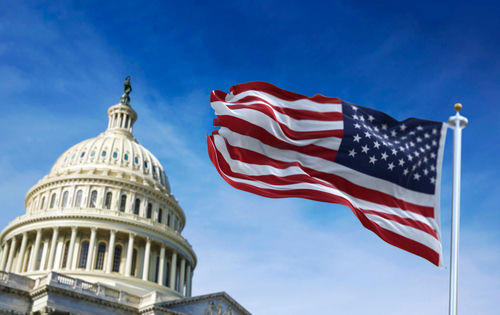 U.S. Capitol building with waving American flag.