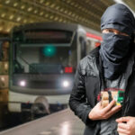 Iranian Sleeper Cells Target America’s Biggest Event… Man with cloth-covered face holding device in subway.