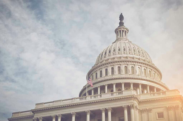 US Capitol dome with American flag and cloudy sky.
