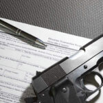Form with gun and pen on table.