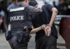 Police officer arresting a person in handcuffs.