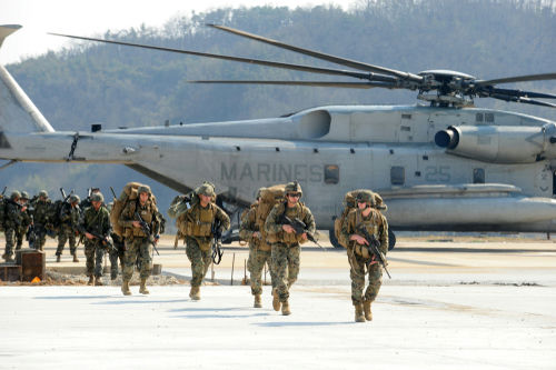 shutterstock_1123252001 Marines walking away from helicopter on airstrip.