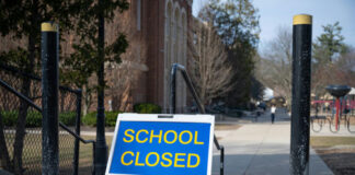 School closed sign on sidewalk near building.