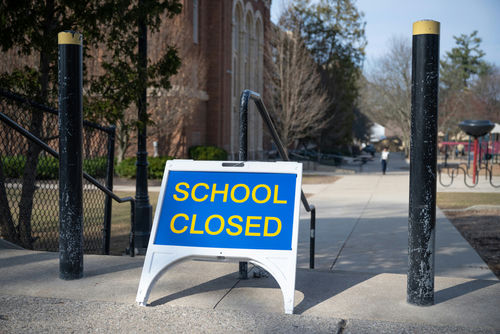 School closed sign on sidewalk near building.