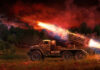 Military truck firing rockets at night.