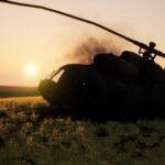 Abandoned military helicopter in a grassy field during sunset