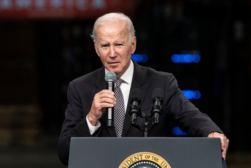 A man in a suit speaking into a microphone at a podium with a presidential seal
