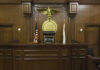 A Judge Released Four Violent Criminals — Murder, Child Sex Crimes, Homicide Judges bench in an empty courtroom, scales emblem above.