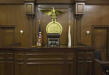 A Judge Released Four Violent Criminals — Murder, Child Sex Crimes, Homicide Judges bench in an empty courtroom, scales emblem above.