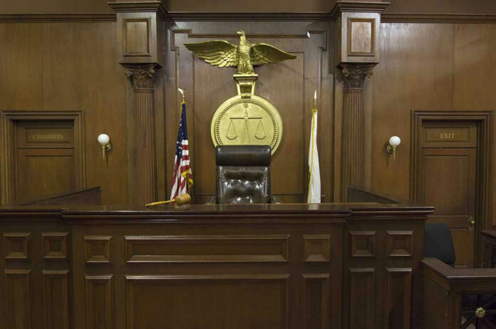 121502698-2 Judges bench in an empty courtroom, scales emblem above.