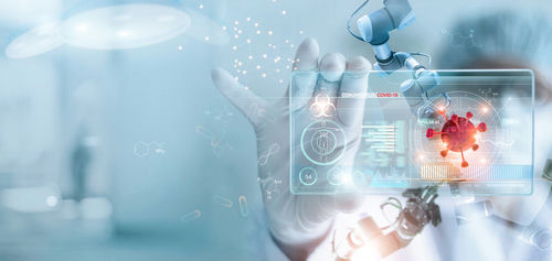 Scientist using robotic arm and digital interface with coronavirus graphic
