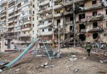 Venezuela: 1,430 Killed, Hospitals Overwhelmed Damaged apartment building with debris scattered firefighters present.