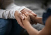 An adult hand holding a childs hand in a warm gesture