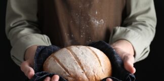 Person holding a freshly baked loaf of bread in a cloth