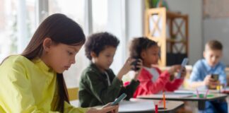 Students using smartphones at classroom desks