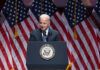 Joe Biden speaking at podium with American flags behind.