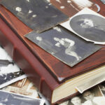 Old family photo album with scattered vintage photographs.