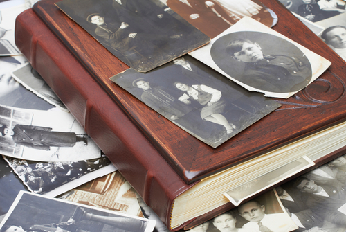 Old family photo album with scattered vintage photographs.