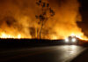 Brush fire on both sides of a road at night.