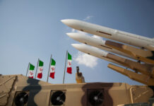 Missiles on launchers beside Iranian flags.