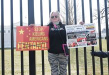 Protester holding fentanyl awareness signs outside White House fence.