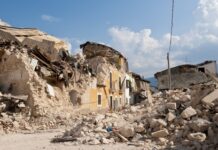 Rubble from collapsed buildings in earthquake-hit area. Clear sky.