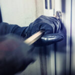 Person breaking into door with crowbar and gloves.