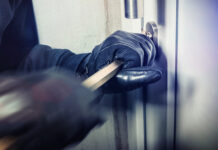 Person breaking into door with crowbar and gloves.